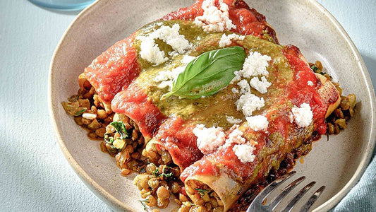 Mit Linsen gefüllte Cannelloni mit Tomatensauce, Feta und Basilikum auf einem Teller.