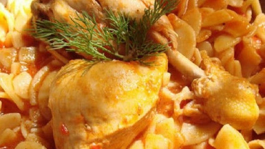 Hahn in roter Weinsauce mit Chilopites-Nudeln, garniert mit Dill.