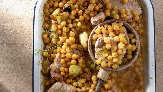 Kichererbsen mit Schweinefleisch, Lauch und Fenchel in einer Auflaufform, mit Löffel.