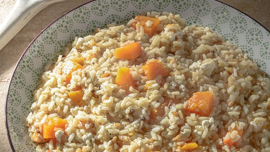 Cremiges Kürbisrisotto mit Kürbisstücken auf einem gemusterten Teller.