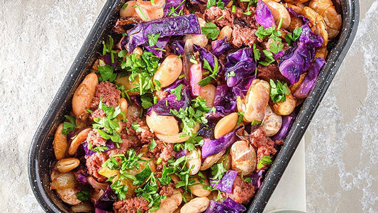 Weiße Riesenbohnen mit Kavourmas und Rotkohl in einer Auflaufform, mit Petersilie.