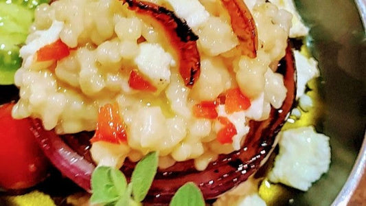 Cremiger Trahanas mit Feta und roten Zwiebeln, garniert mit frischem Oregano.