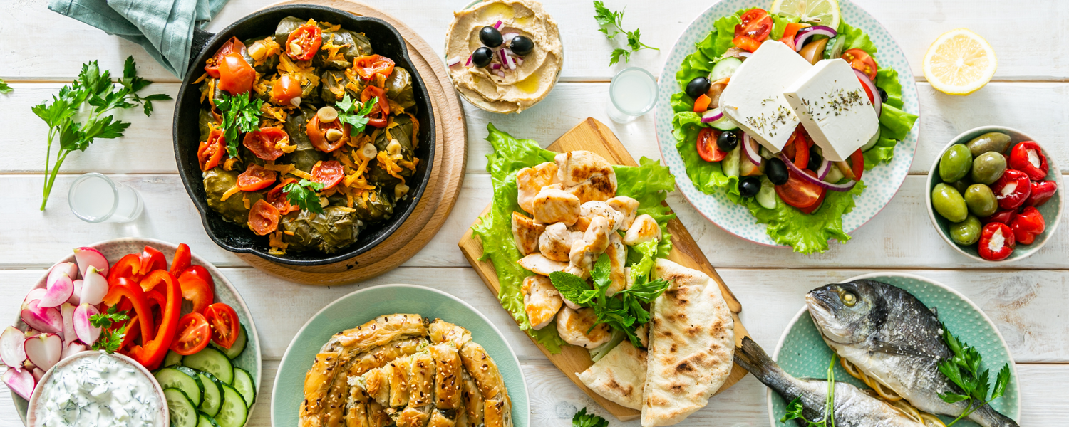 Griechische Mezze-Tafel mit gefüllten Weinblättern, Bauernsalat mit Feta, Hummus, Tzatziki, gegrilltem Fisch, Hähnchen und Oliven